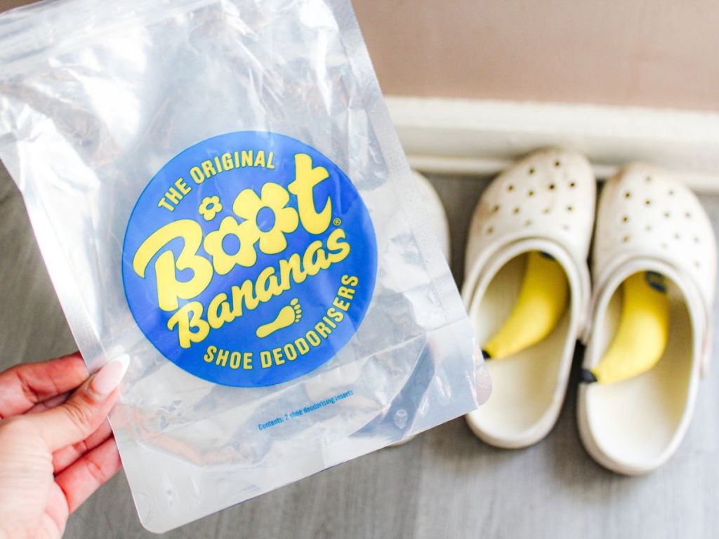 hand holding the empty packaging from a pair of Boot Bananas with the bananas inside a pair of Crocs in the background