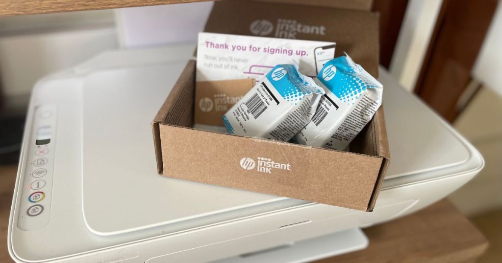 A printer with a box of HP instant ink cartridges in it