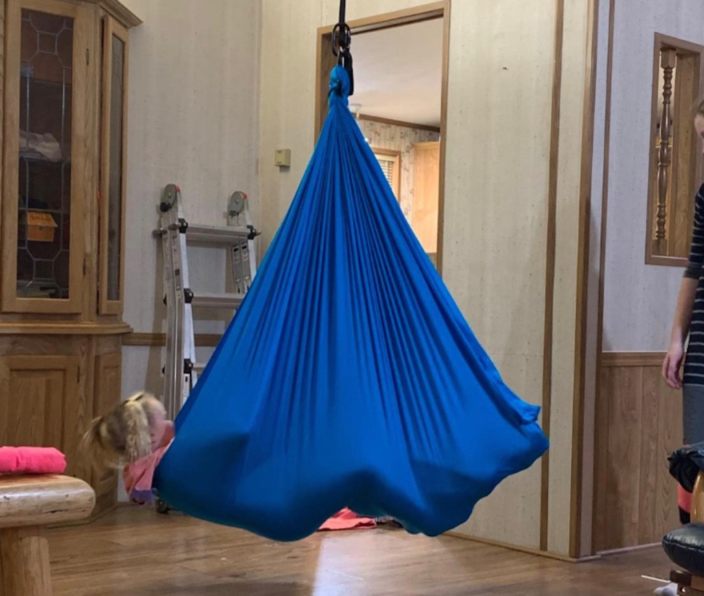 child hanging in blue fabric from ceiling