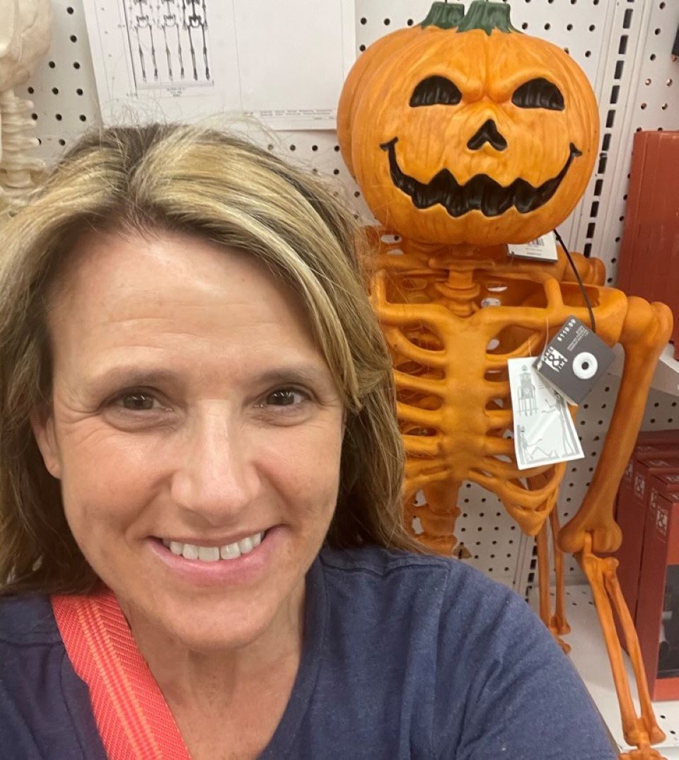 Woman standing in front of a skeleton with a pumpkin head