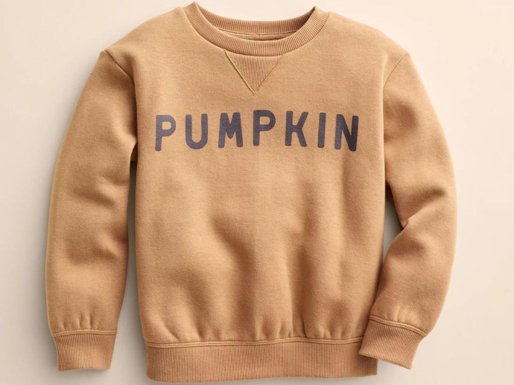 A tan child's sweatshirt with "pumpkin" written on it 