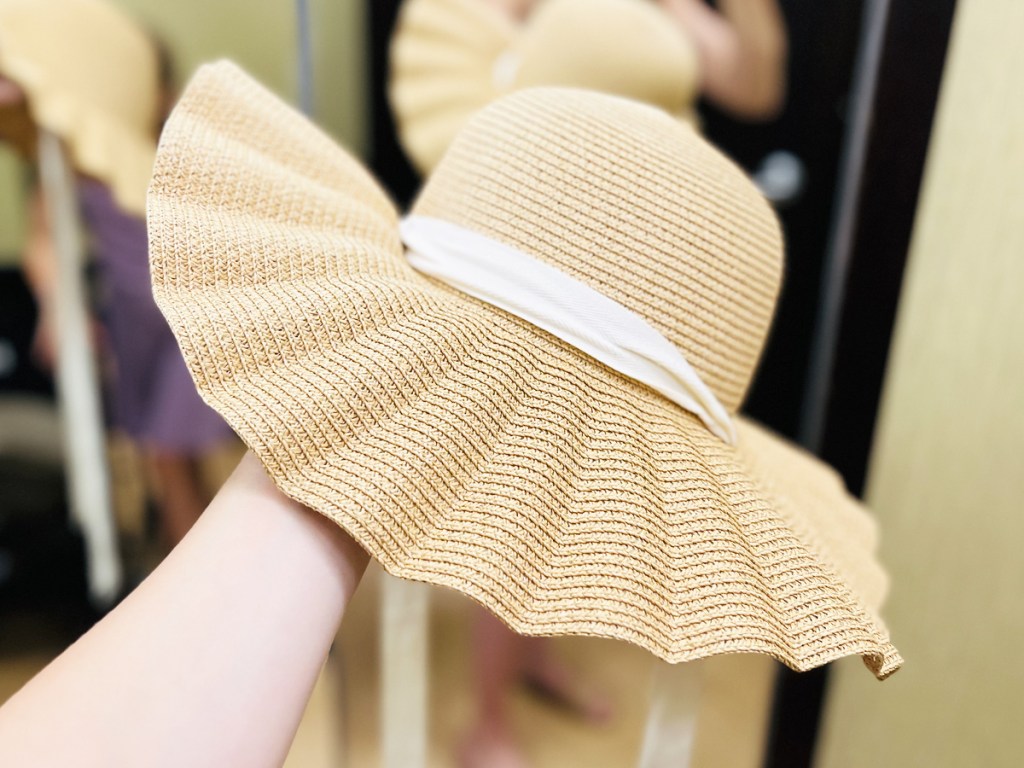 arm holding up a wavy brim sun hat