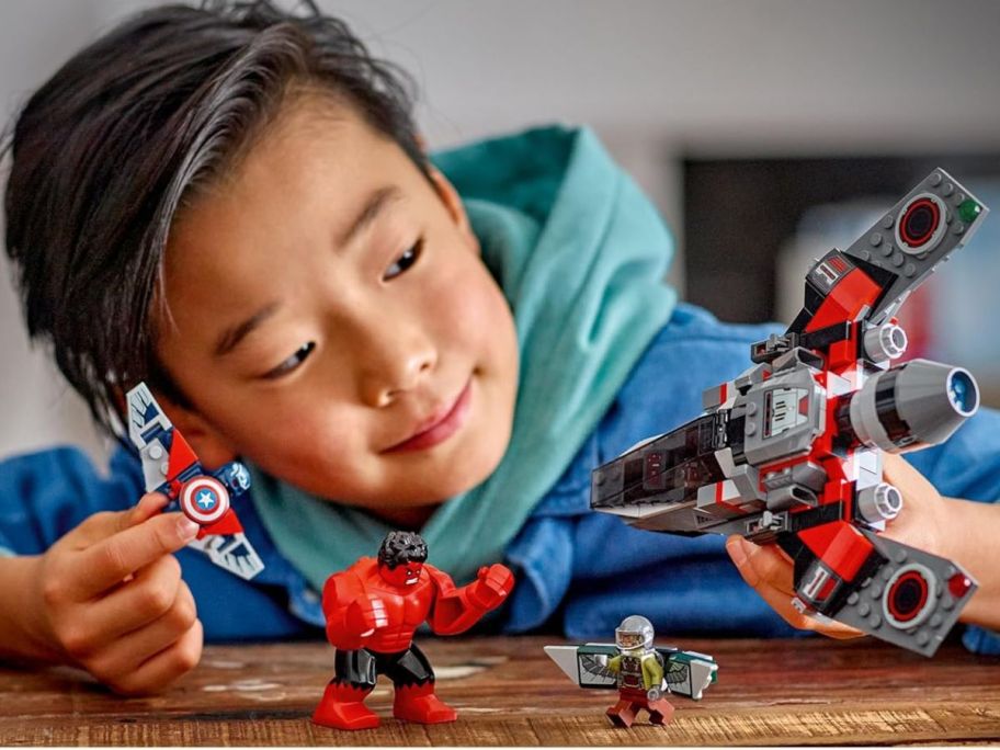Boy playing with a LEGO Marvel Captain America vs. Red Hulk Battle set