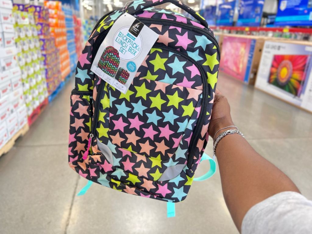 a hand holding a backpack with stars on it
