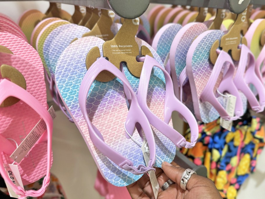 hand holding pair of purple and blue toddler girls flip flops