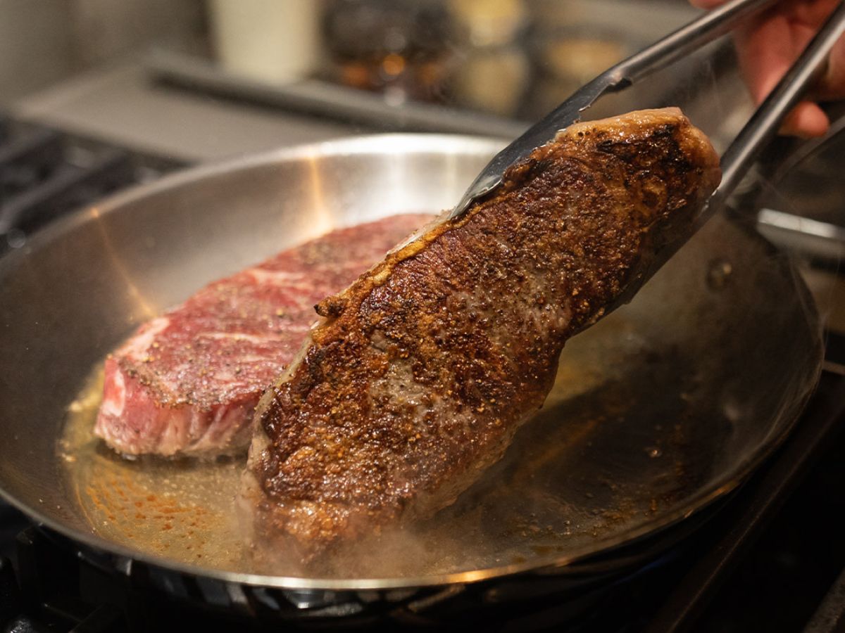 An Omaha Steaks Strip steak being seared in a pan