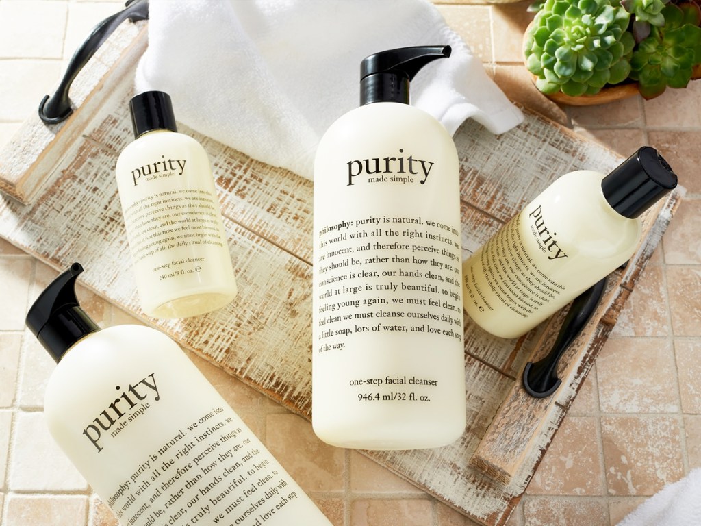 multiple bottles of Philosophy Purity Made Simple One-Step Facial Cleansers on a wood tray