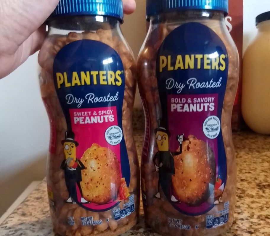 Hand holding a bottle of Planters peanuts