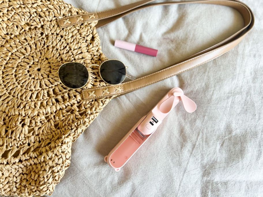 Portable fan next to a purse and sunglasses