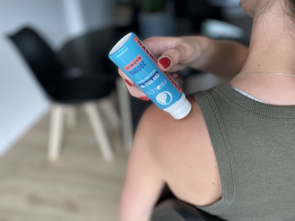 Woman using a CBD roller on her shoulder