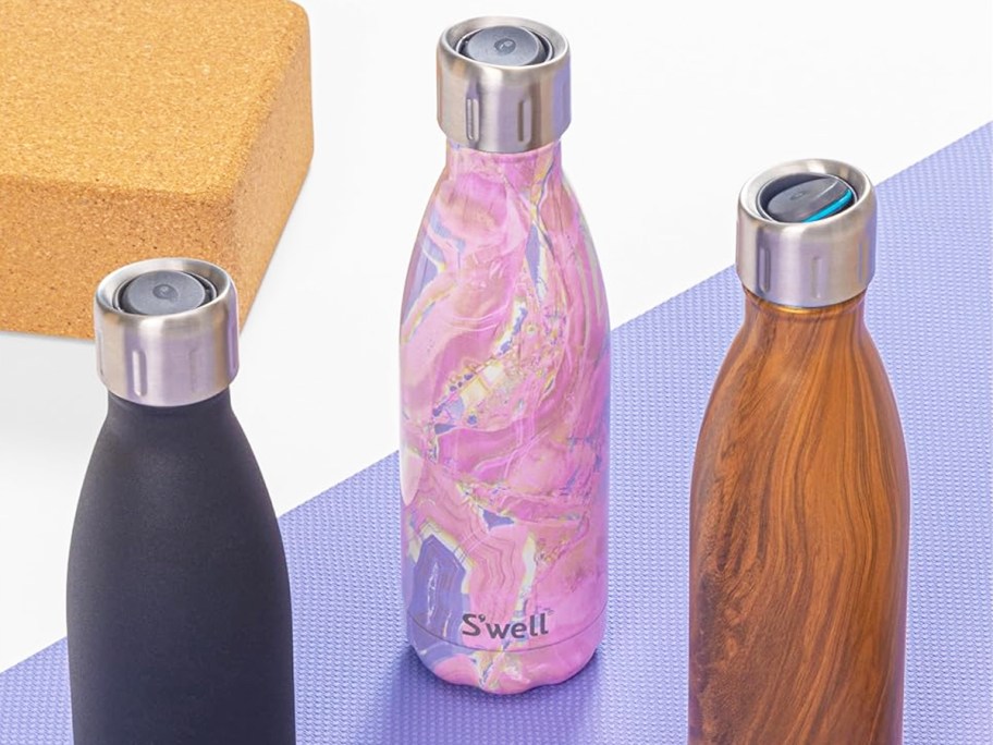 three S'well Stainless Steel Water Bottles on a purple yoga mat