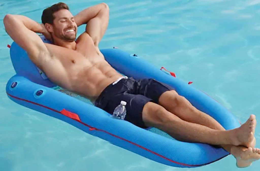 man laying in blue pool lounge in pool