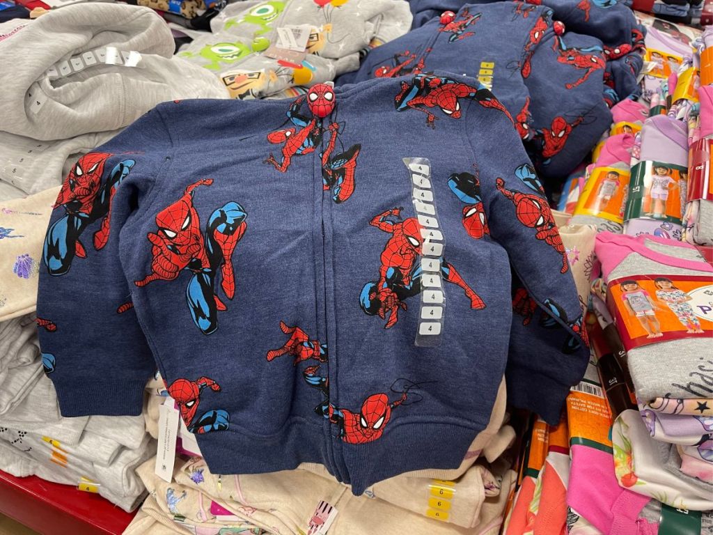 Spiderman zip up hoodie layed out on piles of clothes in store