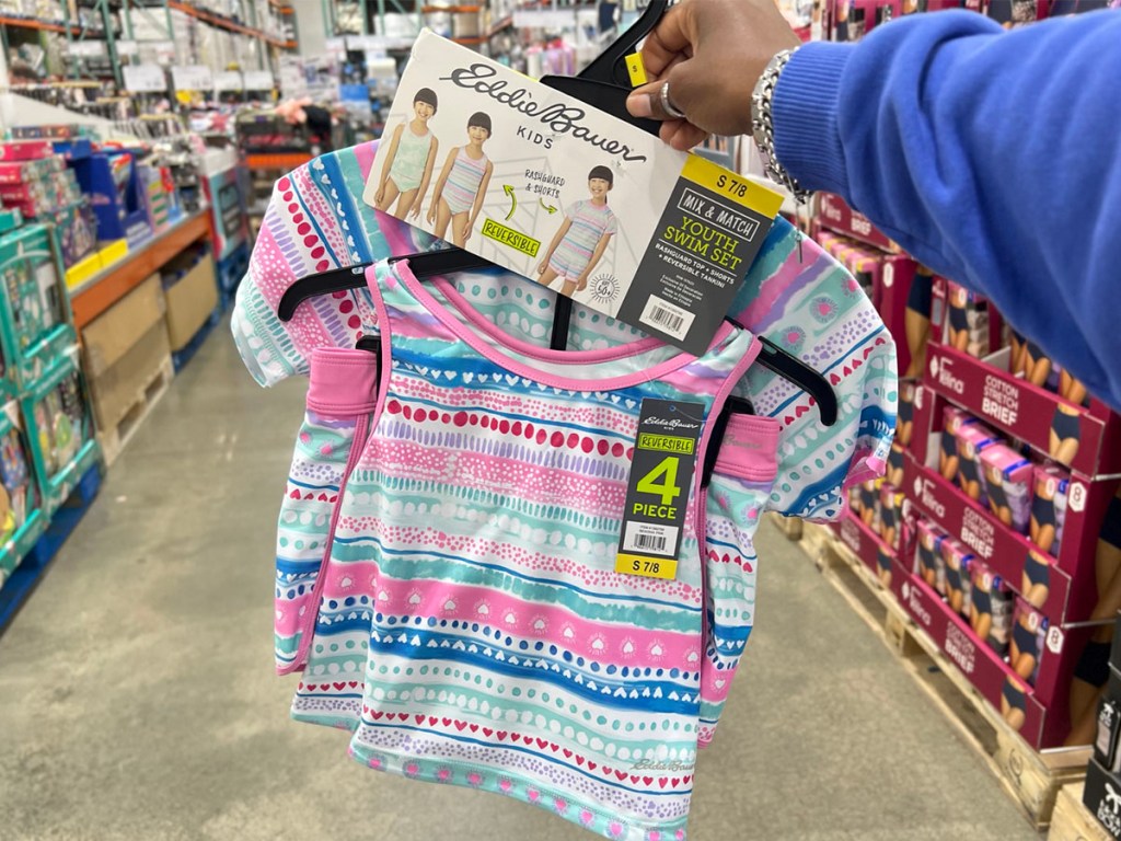 hand holding striped pink and blue swimsuit set