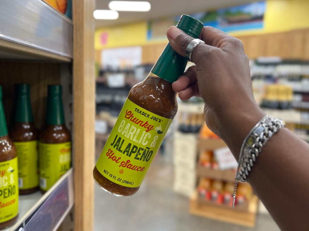 hand holding hot sauce bottle in trader joes