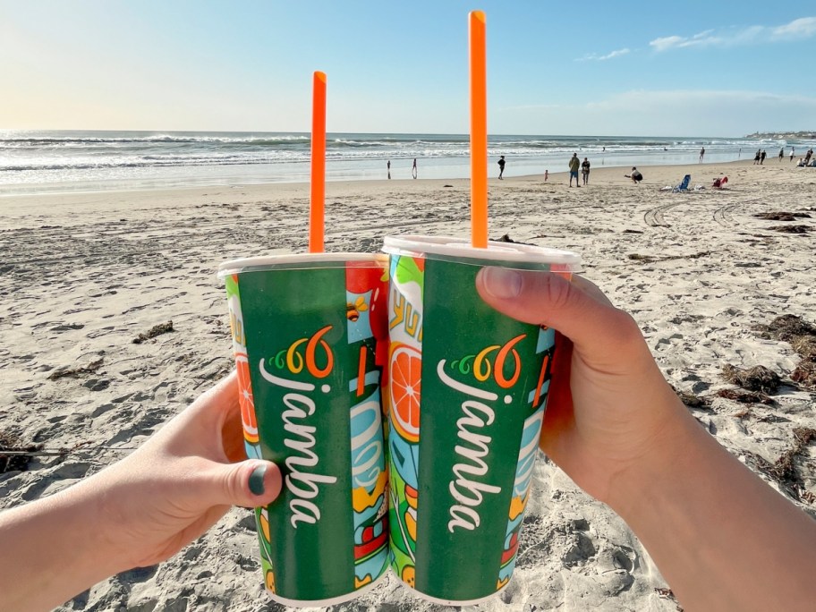 holding 2 smoothies on the beach