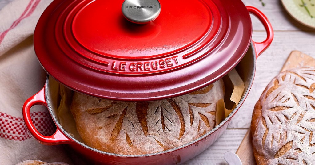 red le creuset dutch oven on table with bread inside