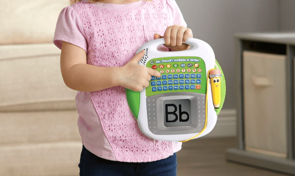 young girl pointing to a lLapFrog Scribble and Write toy 