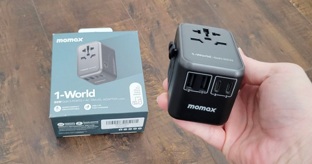 hand holding black momax charger with box on table