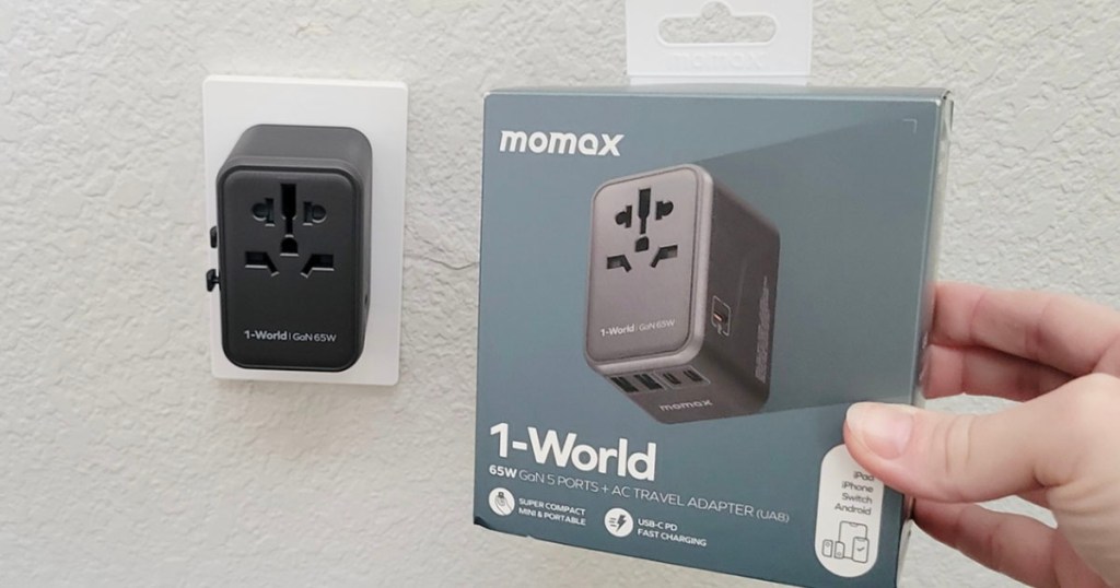 hand holding momax charger box with charger plugged into wall