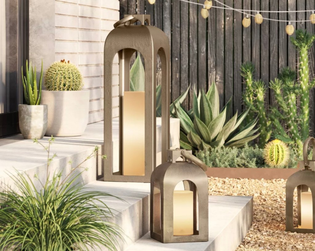 silver metal lanterns outside on concrete steps surrounded by succulent plants