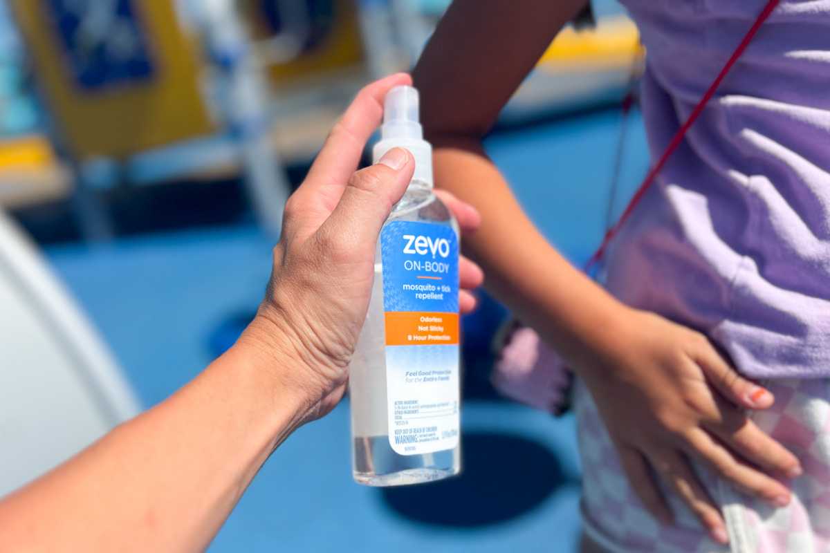 hand spraying little girl with bug repellant