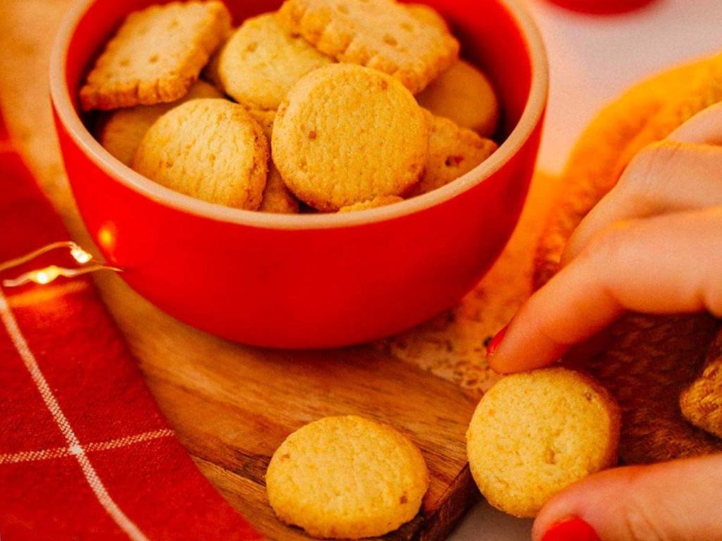 Michel et Augustin Gourmet Cheese Crackers shown in bowl with hand picking 1 up