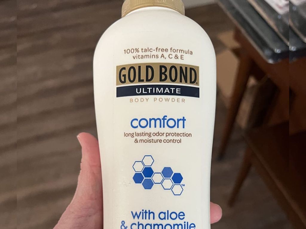 Gold Bond Comfort Body Powder, 10 oz., Talc-Free, Fresh Clean Scent With Aloe & Chamomile shown in woman's hand