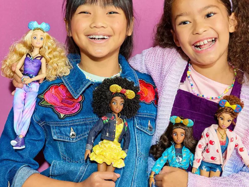 2 girls holding 4 Disney fashion dolls 