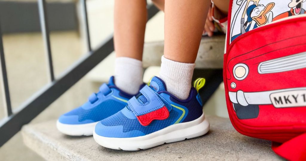 A child sitting on a stoop while wearing a pair of Dream Pairs shoes