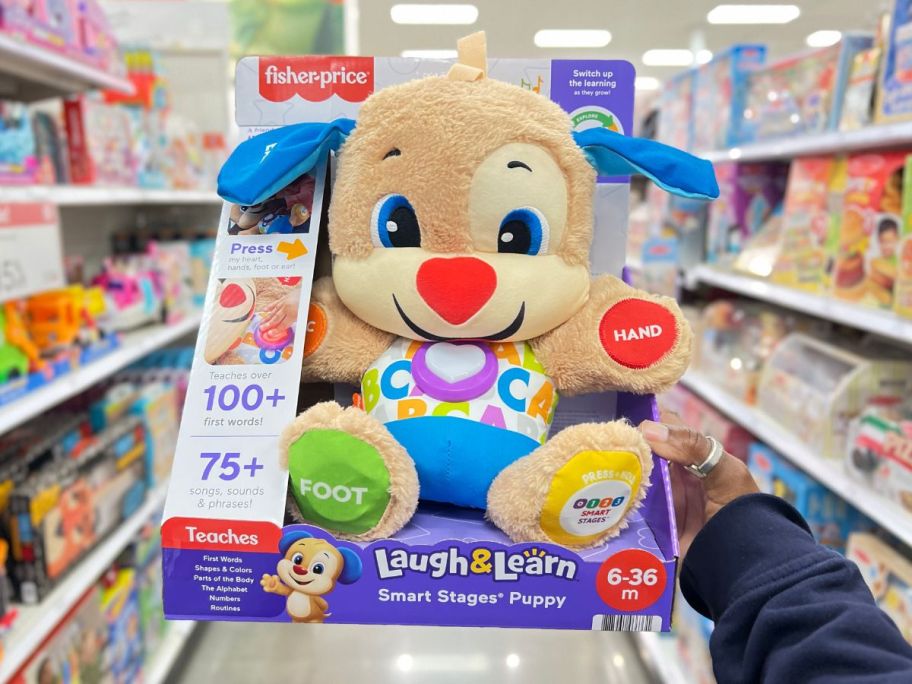 a womans hand holding a and interactive plush puppy