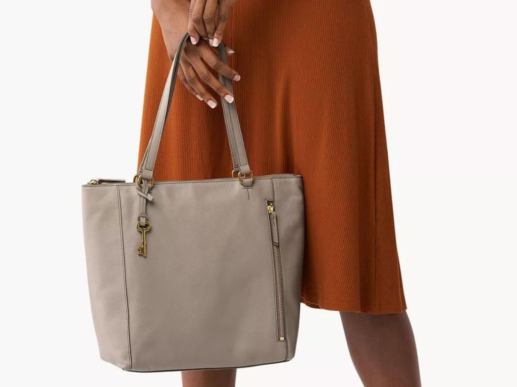 a woman holding a Fossil tote in graystone