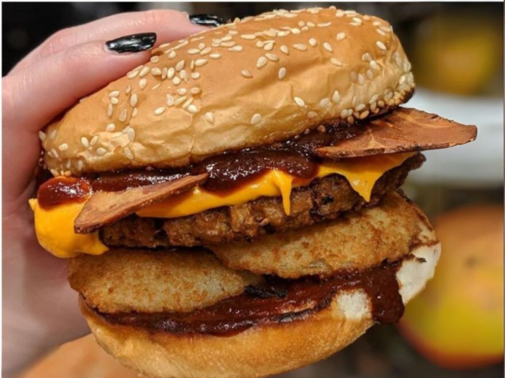 woman's hand holding a Carl's Jr. western bacon cheeseburger