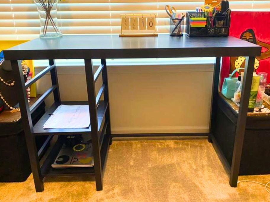 black desk with storage shelves in a room with flowers and other items on it