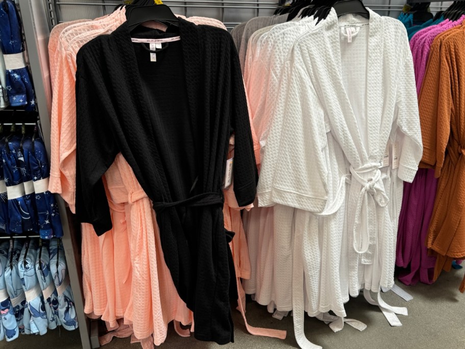 black, white and pink women's waffle knit long sleeve robes hanging in store