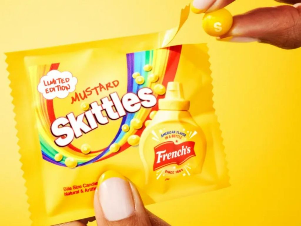 Skittles Mustard bag shown in woman's hand with a yellow mustard Skittle