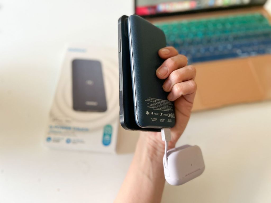MOMAX Wireless Portable Charger Power Bank shown with phone and AirPods charging