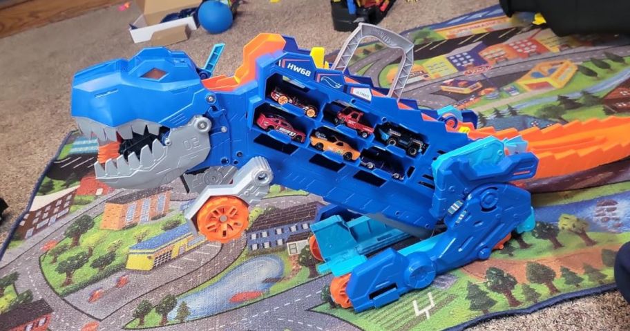 Hot Wheels City Ultimate T-Rex Transporter Set filled with cars on a carpet