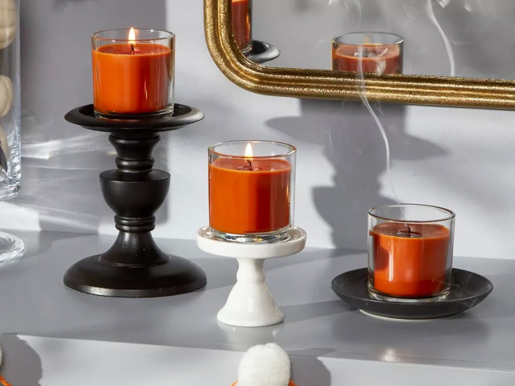 three orange votive candles on top of candle holders