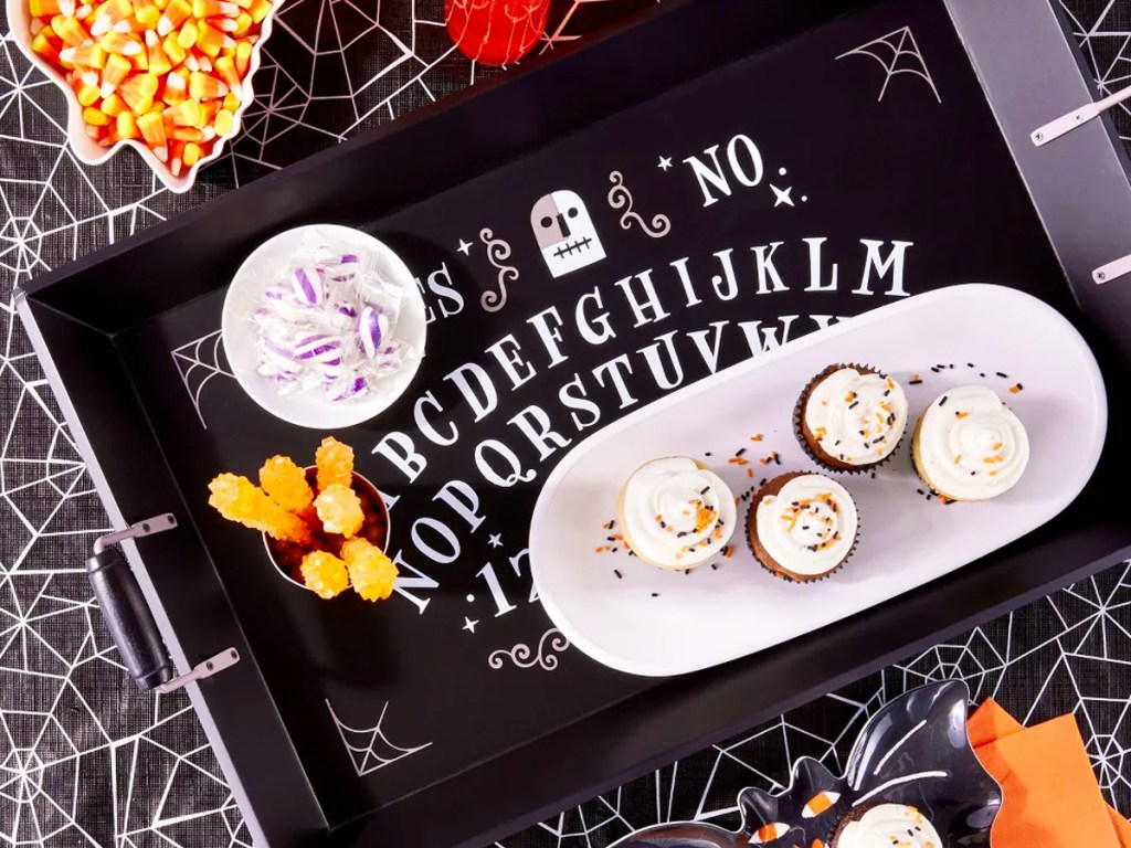 black serving tray with plate of cupcakes and candy on top