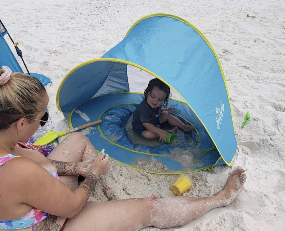 baby in blue pop up pool in sand with shade