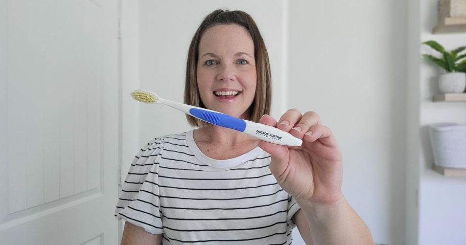 woman holding blue & white toothbrush up to the camera