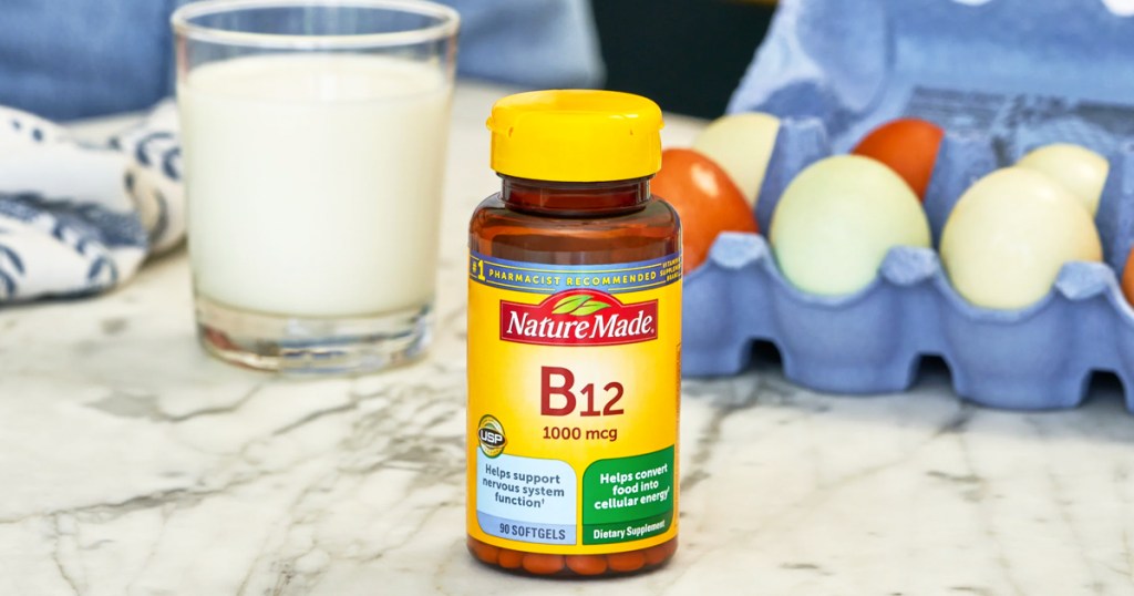 bottle of Nature Made Vitamin B12 near glass of milk and carton of eggs