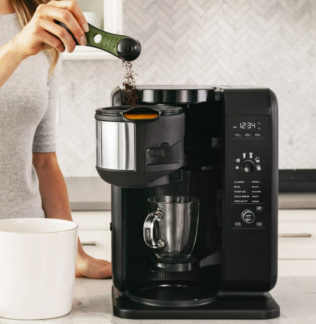 woman putting a scoop of ground coffee into a coffee maker