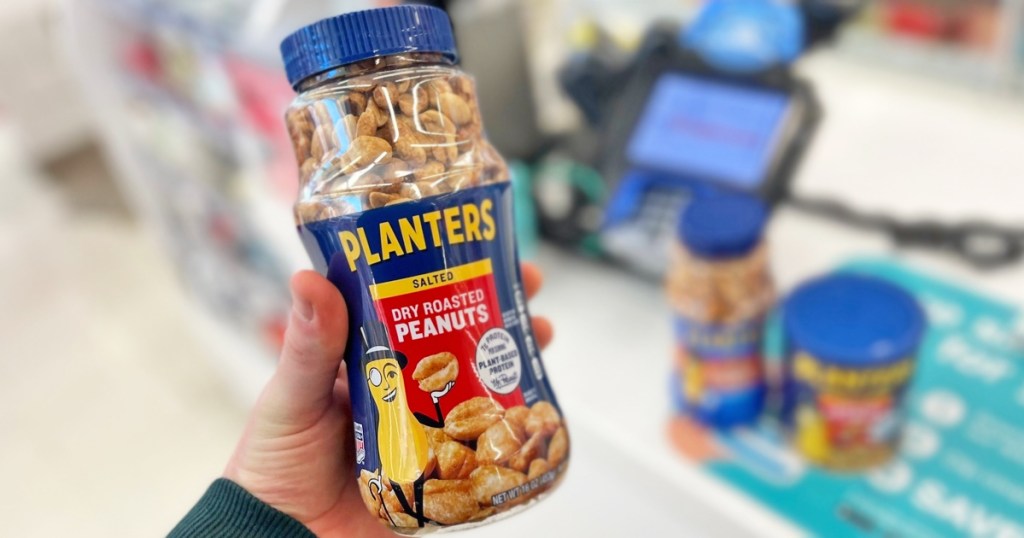 hand holding a jar of planters peanuts