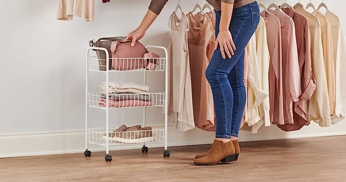 white 3-tier cart in closet with bags, tops, and shoes in them