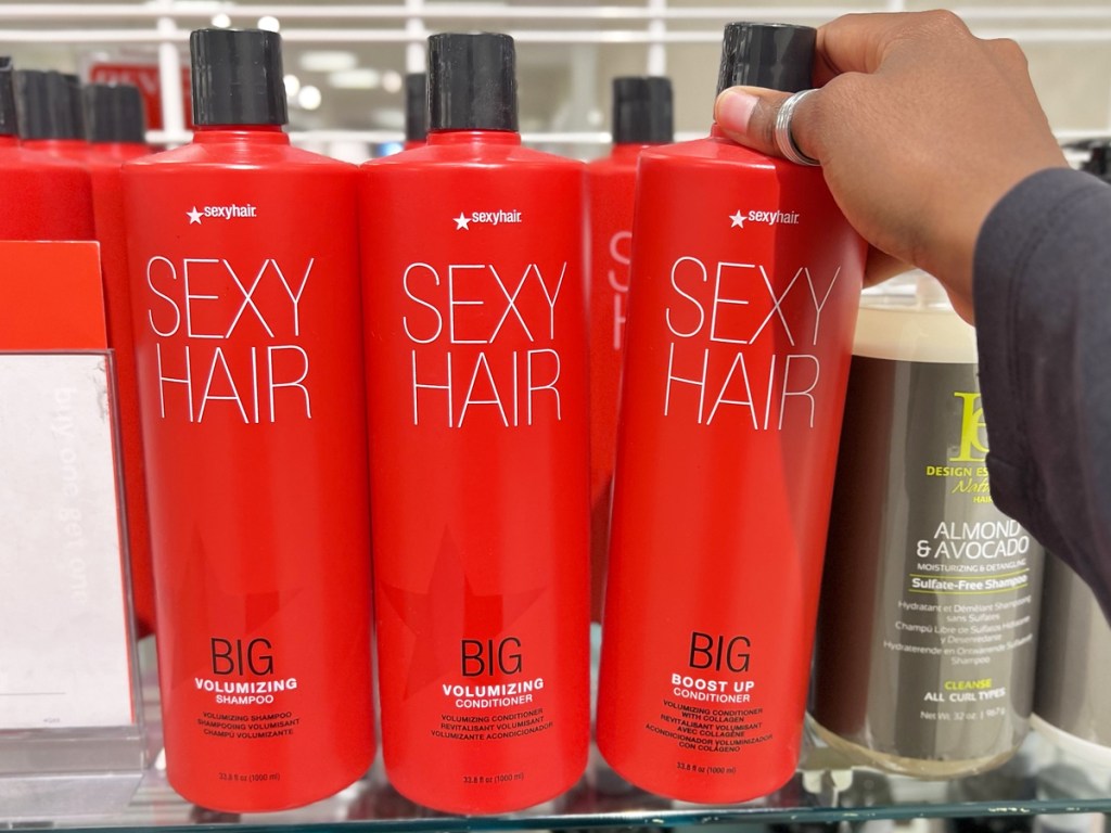 hand touching 1-liter bottles of sexy hair shampoo and conditioner