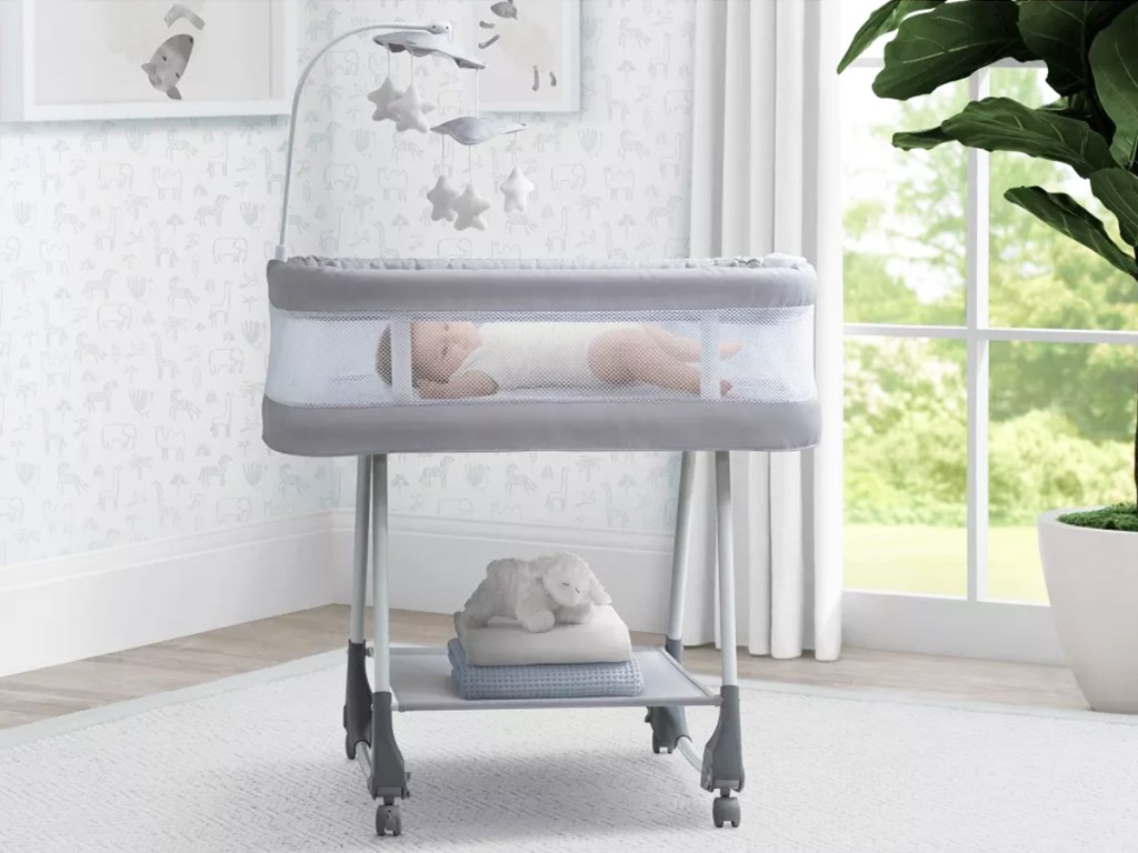 baby in a grey rolling bassinet