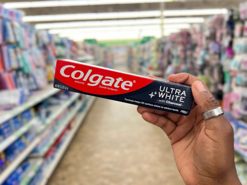 A hand holding a toothpaste box