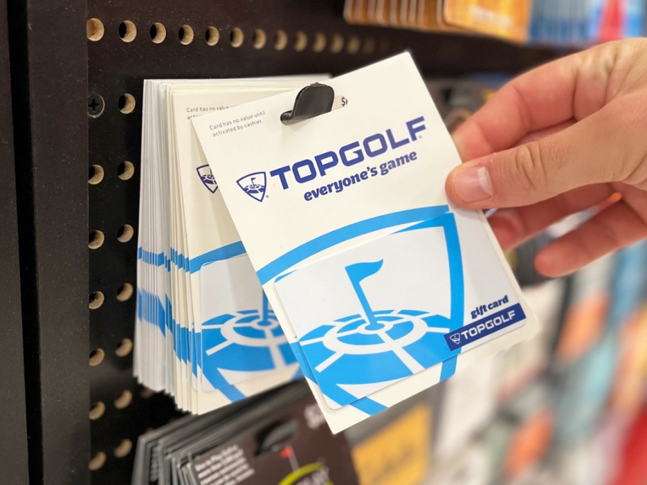 hand grabbing a topgolf gift card from store display